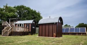 two small buildings with solar panels on a field at Get Away Hide Away in East Dereham
