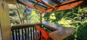 a balcony with a wooden table and two chairs at Rameka Chalet in Takaka