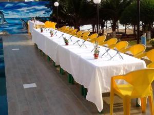 a group of long tables and yellow chairs next to a pool at Nima Resort et Suites in Mandanou