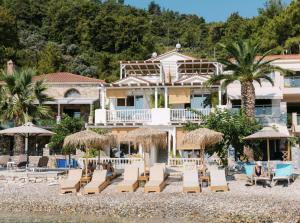 a hotel on the beach with chairs and umbrellas at Aegean Stories pelagos suites in Avlákia