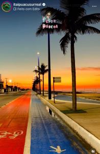 a street with palm trees on a beach at sunset at Casa em Maricá- Paraiso Itaipuaçu in Maricá