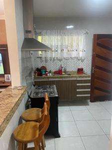a kitchen with a stove and two chairs in it at Casa em Maricá- Paraiso Itaipuaçu in Maricá