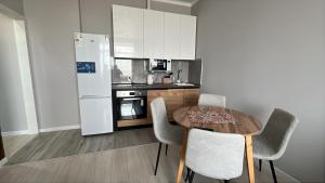 a kitchen with a wooden table and a white refrigerator at Dostar Apartments in Karagandy