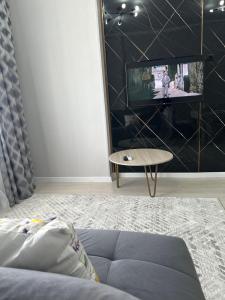 a living room with a couch and a tv at Dostar Apartments in Karagandy +2 photos