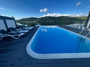 a swimming pool with lounge chairs next to a body of water at Panorama Lake Resort in Bezidu Nou