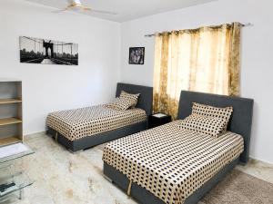 a room with two beds and a couch and a window at Big Papa Hotel in Amasaman