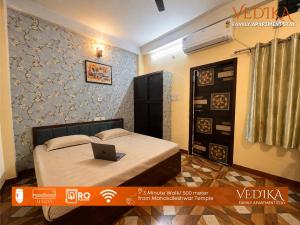 a bedroom with a bed with a laptop on it at Vedika Yatri Grah - Entire Apartment in Ujjain