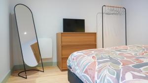 a bedroom with a bed and a dresser with a television at Le Perchoir d'Orthez in Orthez