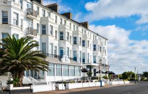 a white building with a palm tree in front of it at Langham Hotel Eastbourne in Eastbourne