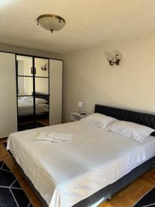 a bedroom with a large white bed with a mirror at Capital apartman in Visoko