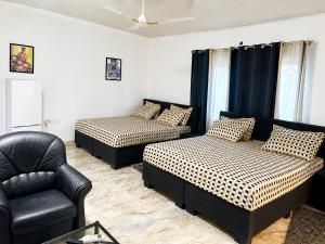 a room with two beds and a couch and a chair at Big Papa Hotel in Amasaman