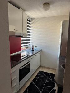 a kitchen with white cabinets and a black floor at Capital apartman in Visoko