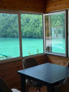 a table and chairs in a room with two windows at Drini Guesthouse in Tropojë