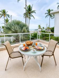 a table with food on a balcony with palm trees at Makai Hotel Boutique - Frente Mar in Guarujá