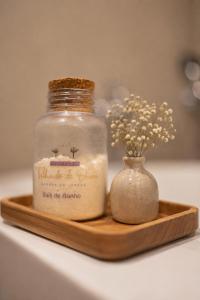 a jar of candle and a vase of flowers on a wooden tray at Pousada Telhado de Ouro in Campos do Jordão