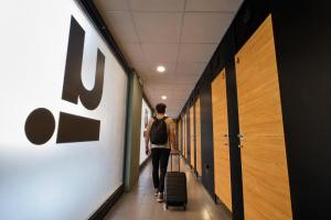 a man walking down a hallway with luggage at U-nit Hostel Central Park in Valencia