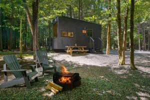 a black tiny house in the woods with a fire at Postcard Cabins Beaver Creek Ohio, Outdoor Collection by Marriott Bonvoy in Lisbon