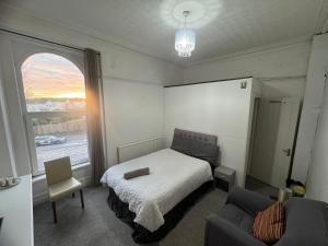 a bedroom with a bed and a couch and a window at Singleton Double Studio Room with Private En-Suite in Sketty +8 photos