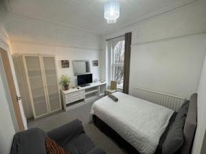 a bedroom with a bed and a couch and a television at Singleton Double Studio Room with Private En-Suite in Sketty
