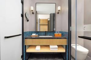 a bathroom with a sink and a toilet and a mirror at Four Points by Sheraton Leshan in Leshan +14 photos
