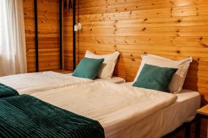 two beds in a room with wooden walls at Cottage Deera in Mestia