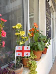 a window with flowers and a sign with a flag on it at Legacy Rooms in Old Tbilisi FREE parking in Tbilisi City