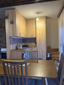 a kitchen with a table and chairs and a kitchen with wooden cabinets at Villa Harmonia in Ferizaj