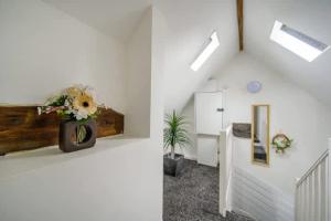 a white room with a staircase with a vase of flowers at RB1GH- Cosy Room SECURE PARKING NEAR CITY CENTRE FAST WIFI in Bramley