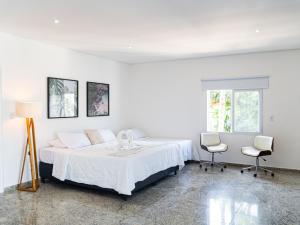 a white bedroom with a bed and two chairs at Makai Hotel Boutique - Frente Mar in Guarujá