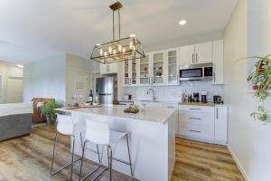 a kitchen with white cabinets and a island with bar stools at Unwind centrally in West Kelowna