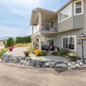 a house with a stone retaining wall and a driveway at Unwind centrally in West Kelowna