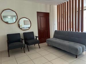 a living room with a couch and two chairs and a mirror at Hermoso condominio frente al mar in San Carlos
