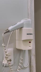 a white hair dryer hanging on a wall at Emburi Hotel in Piratininga