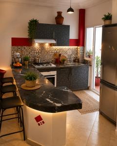 a kitchen with a black counter top and a refrigerator at chic appart vue sur piscine in Tangier
