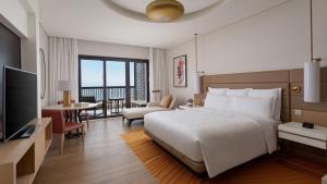 a bedroom with a large bed and a living room at InterContinental Fujairah Resort by IHG in Al Aqah