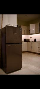 a kitchen with a black refrigerator and white cabinets at White420 apartment in Rawalpindi