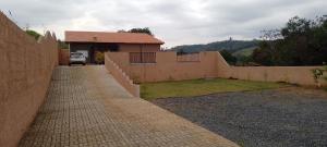 a house with a brick wall and a driveway at Chácara Anna Julia in Piedade