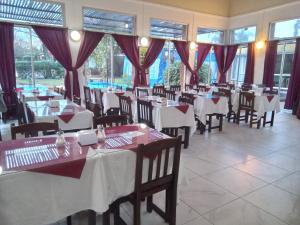 a restaurant with white tables and chairs and windows at Brisas Del Rio Apart Hotel in Termas del Daymán