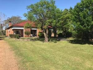 a brick house with a tree in the yard at Brisas Del Rio Apart Hotel in Termas del Daymán