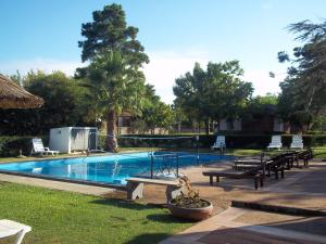 a swimming pool with benches and tables in a park at Brisas Del Rio Apart Hotel in Termas del Daymán