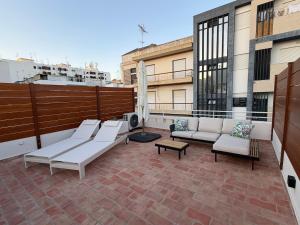 a patio with couches and tables on a balcony at AL do Barão - Casa de Charme com Piscina Privada in Vila Real de Santo António