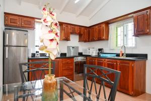 a kitchen with wooden cabinets and a glass table with a flower at Piton Views & Sunset Balcony, Minutes to Beaches in Soufrière +6 photos