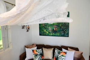 a curtain hanging over a couch with a painting at Piton Views & Sunset Balcony, Minutes to Beaches in Soufrière