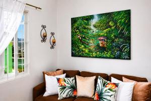 a living room with a couch and a painting on the wall at Piton Views & Sunset Balcony, Minutes to Beaches in Soufrière