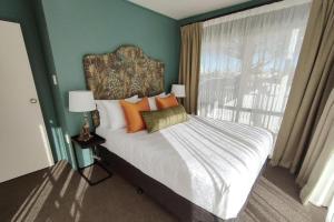 a bedroom with a bed with orange pillows and a window at City Close Motel in Napier