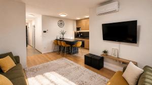 a living room with a couch and a television on a wall at Apartman PEPI LUXURY in Novi Zagreb