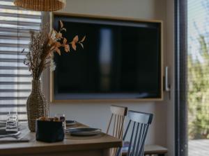 a dining room table with a vase of flowers and a television at Guesthouse Spa Seeblick in Breitenbrunn