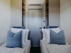 two beds with blue pillows in front of a door at Guesthouse Spa Seeblick in Breitenbrunn