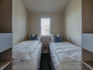 two beds in a small room with a window at Guesthouse Naturgarten in Breitenbrunn