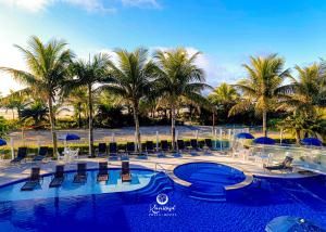 a resort with chairs and palm trees and a pool at Kaakupe Praia Hotel in Guaratuba